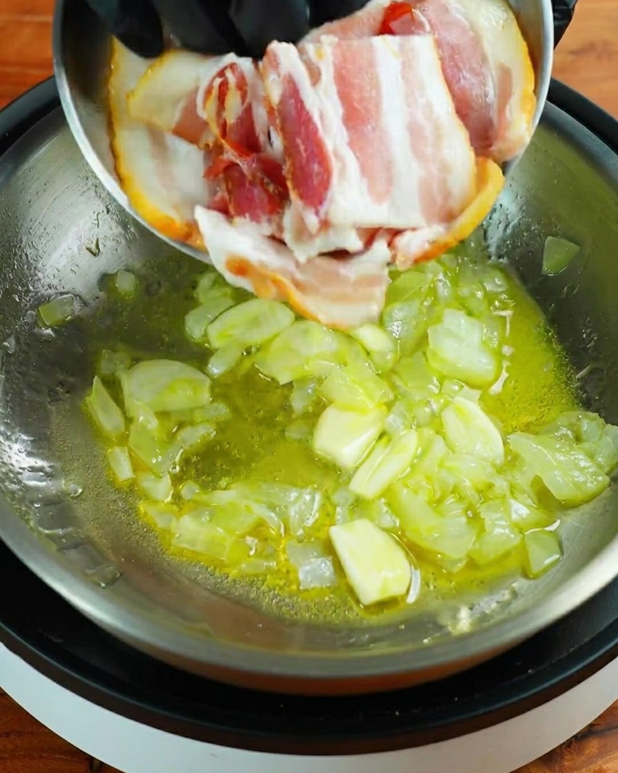 Tre strisce di pancetta cruda aggiunte in padella con aglio e cipolla.