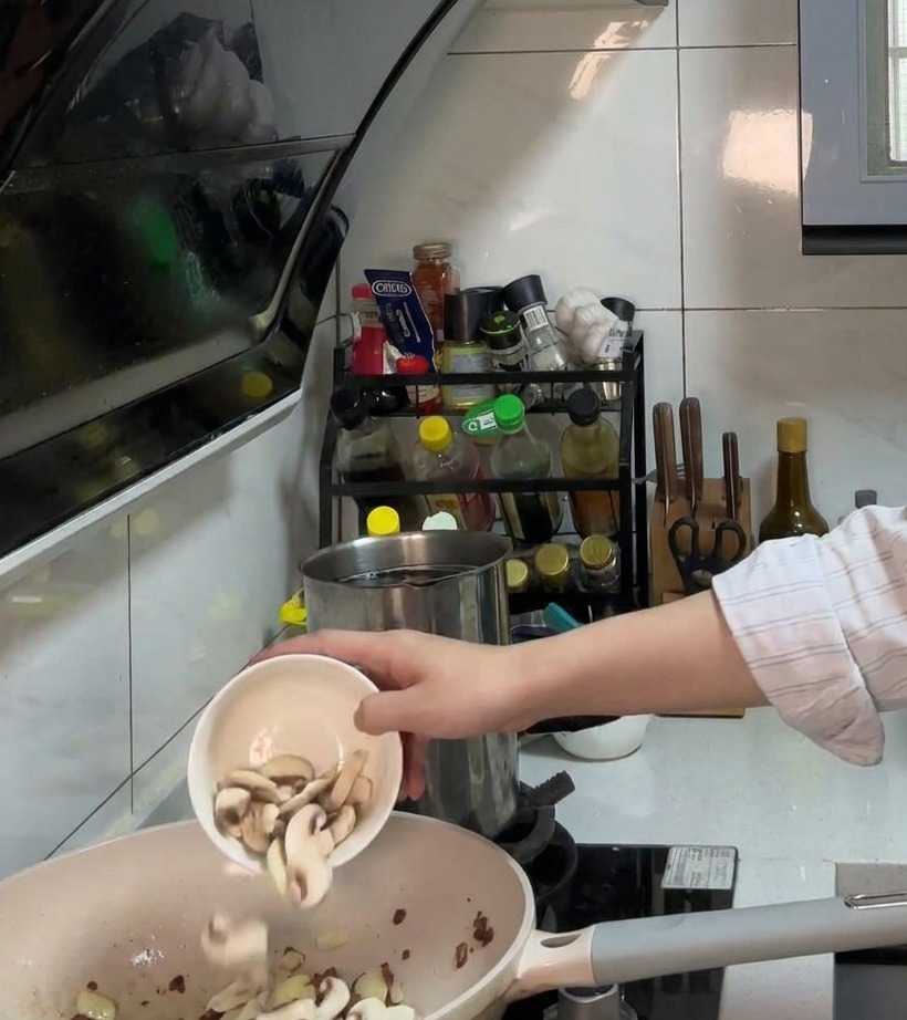 Cipolla tritata e funghi a fette che cuociono in padella con la pancetta.