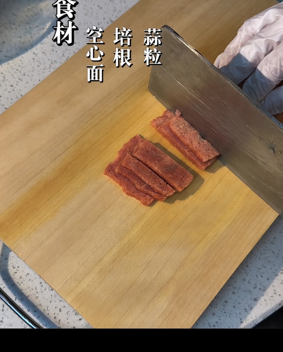 Strisce di bacon tagliate a pezzetti su un tagliere di legno.