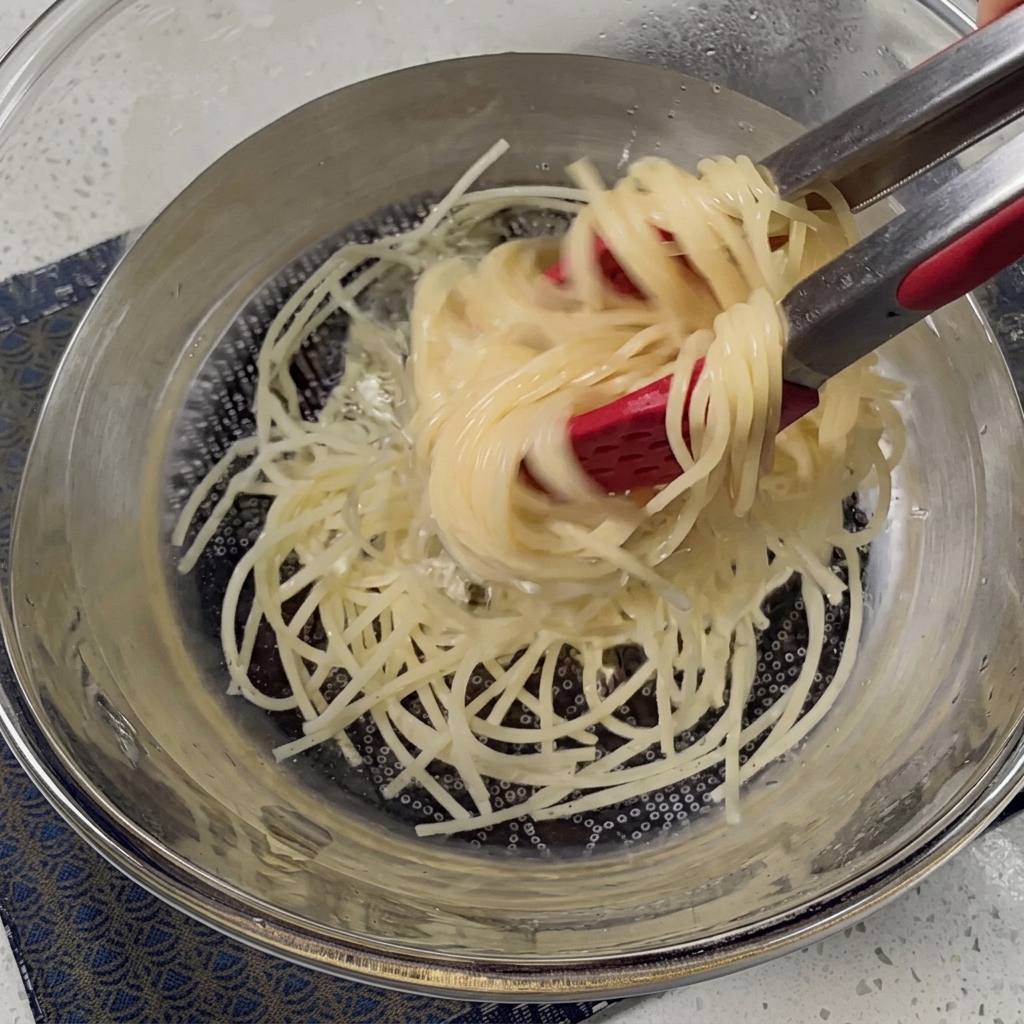 Spaghetti cotti scolati in uno scolapasta di metallo.