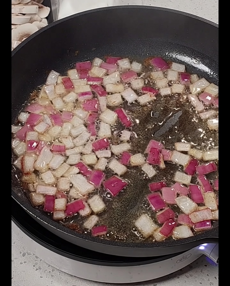 Strisce di pancetta aggiunte in padella con le cipolle appassite.