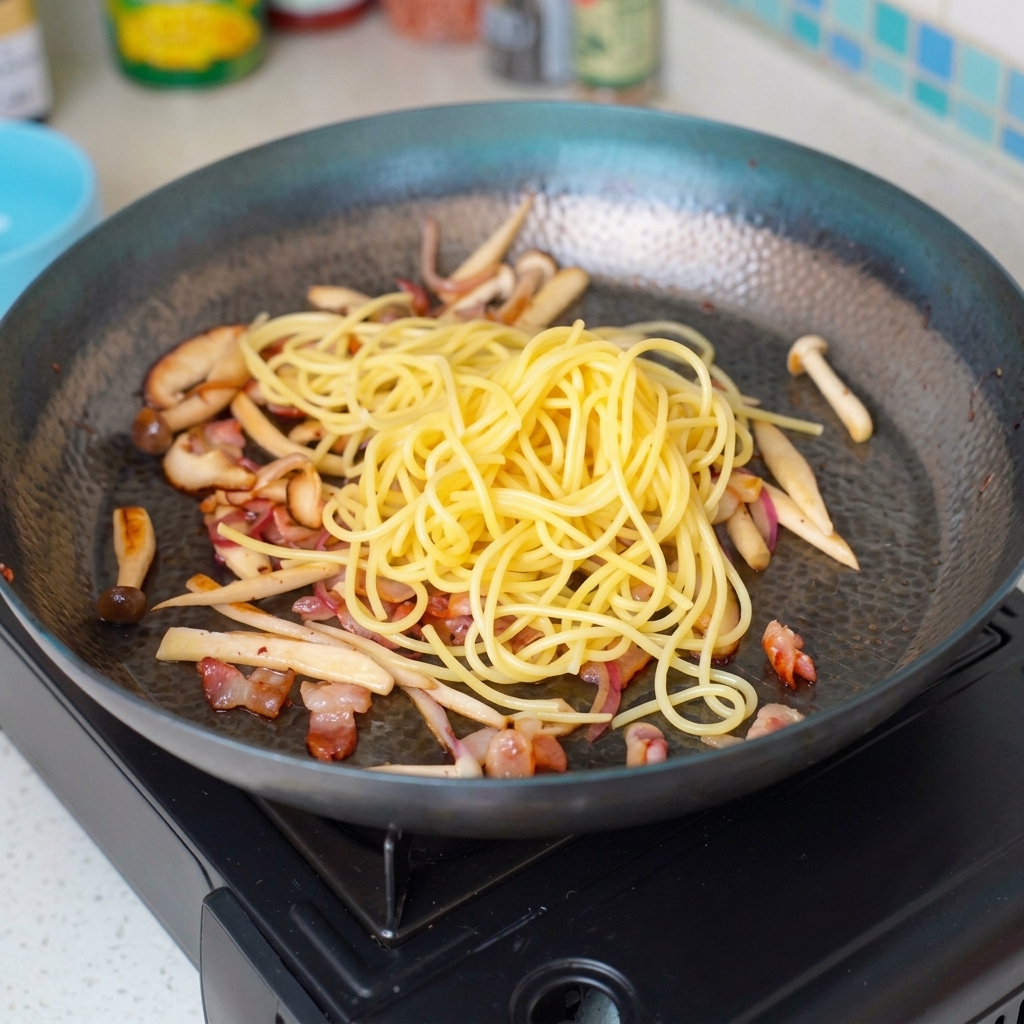 Capellini mescolati agli ingredienti saltati nella padella.