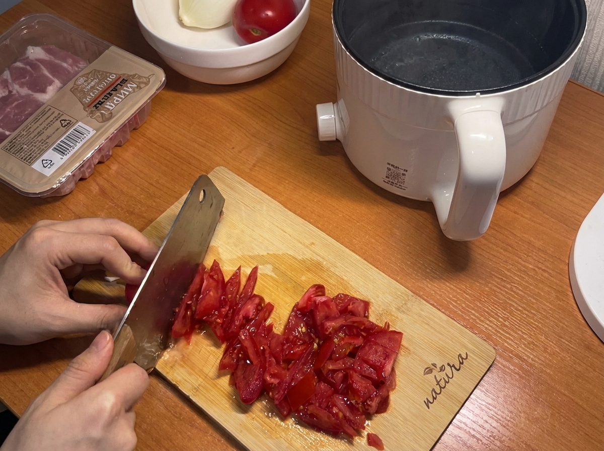 Pomodori rossi freschi tagliati a piccoli pezzi su un tagliere di legno.