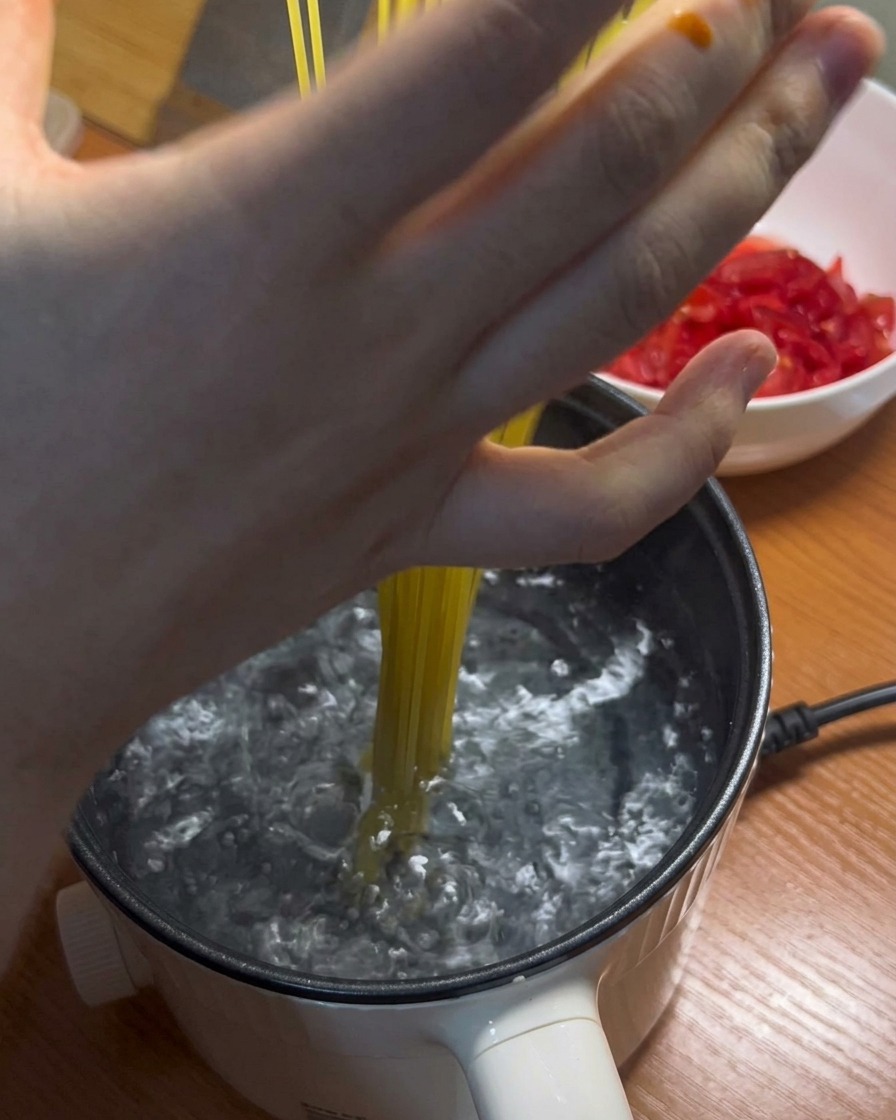 Spaghetti lunghi inseriti in una pentola di acqua bollente.