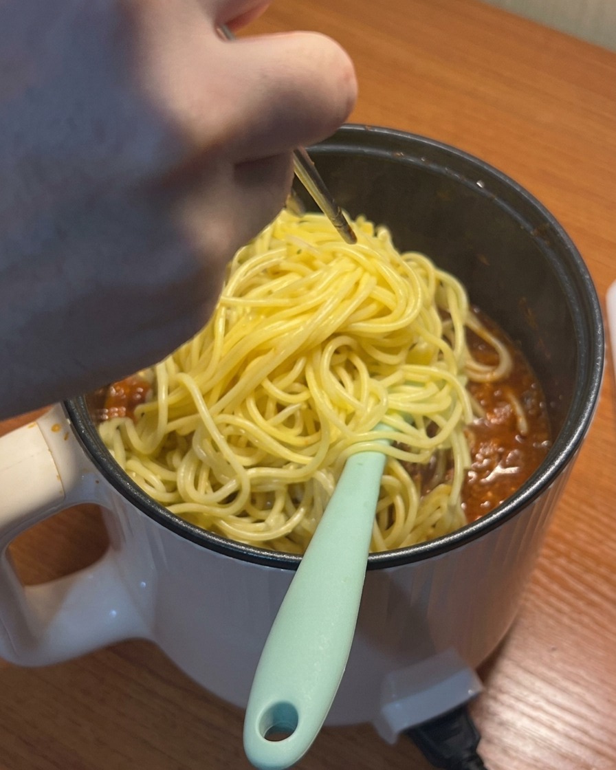 Spaghetti cotti aggiunti al ragù di pomodoro bollente.