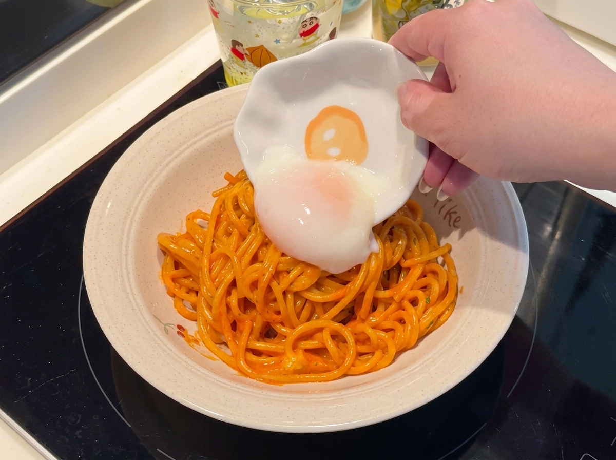 Un uovo barzotto posizionato sopra il piatto di spaghetti piccanti.