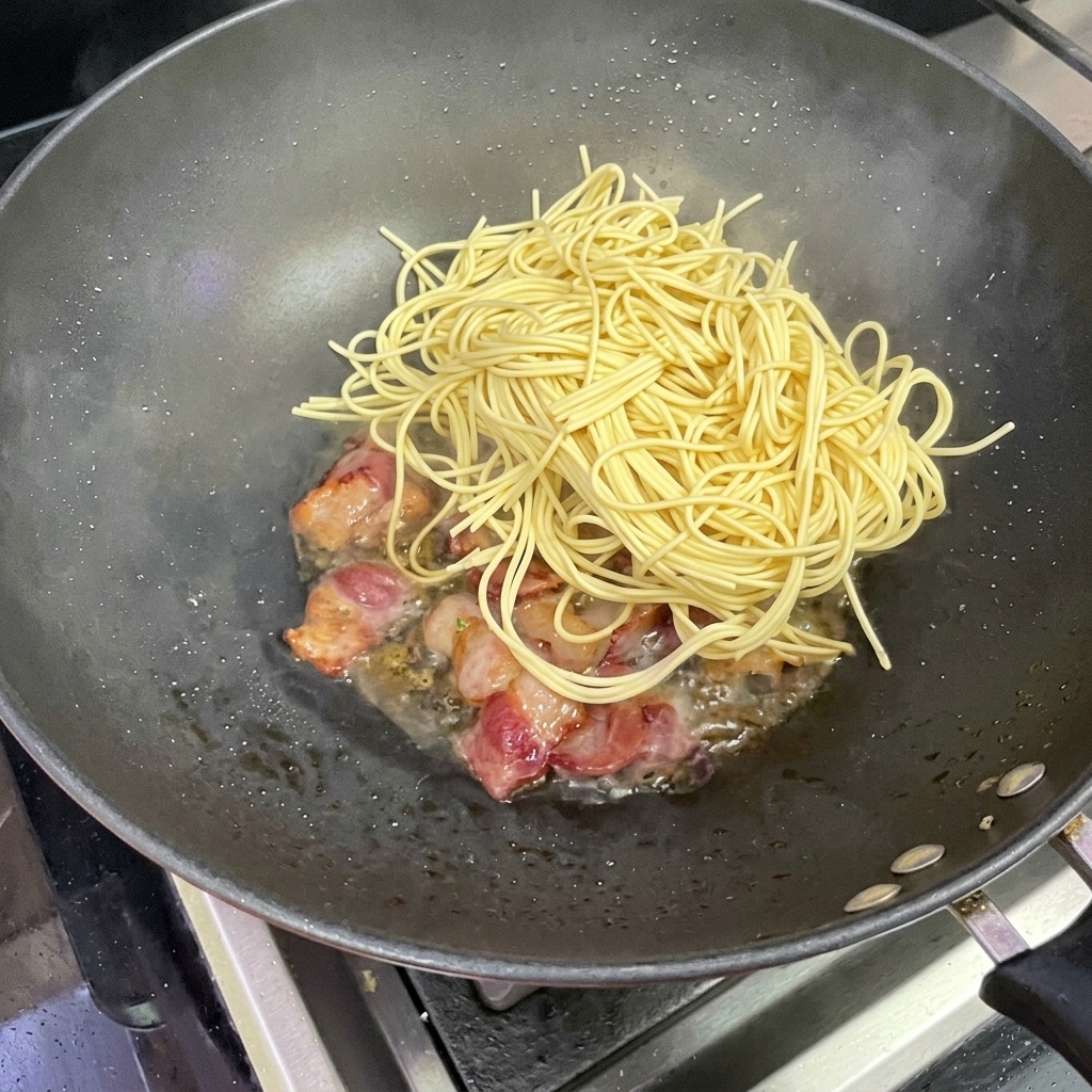 Spaghetti aggiunti nel wok con il bacon.