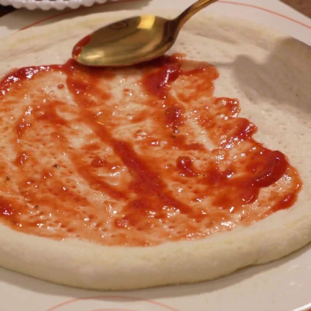 La salsa di pomodoro distribuita uniformemente sulla base della pizza.