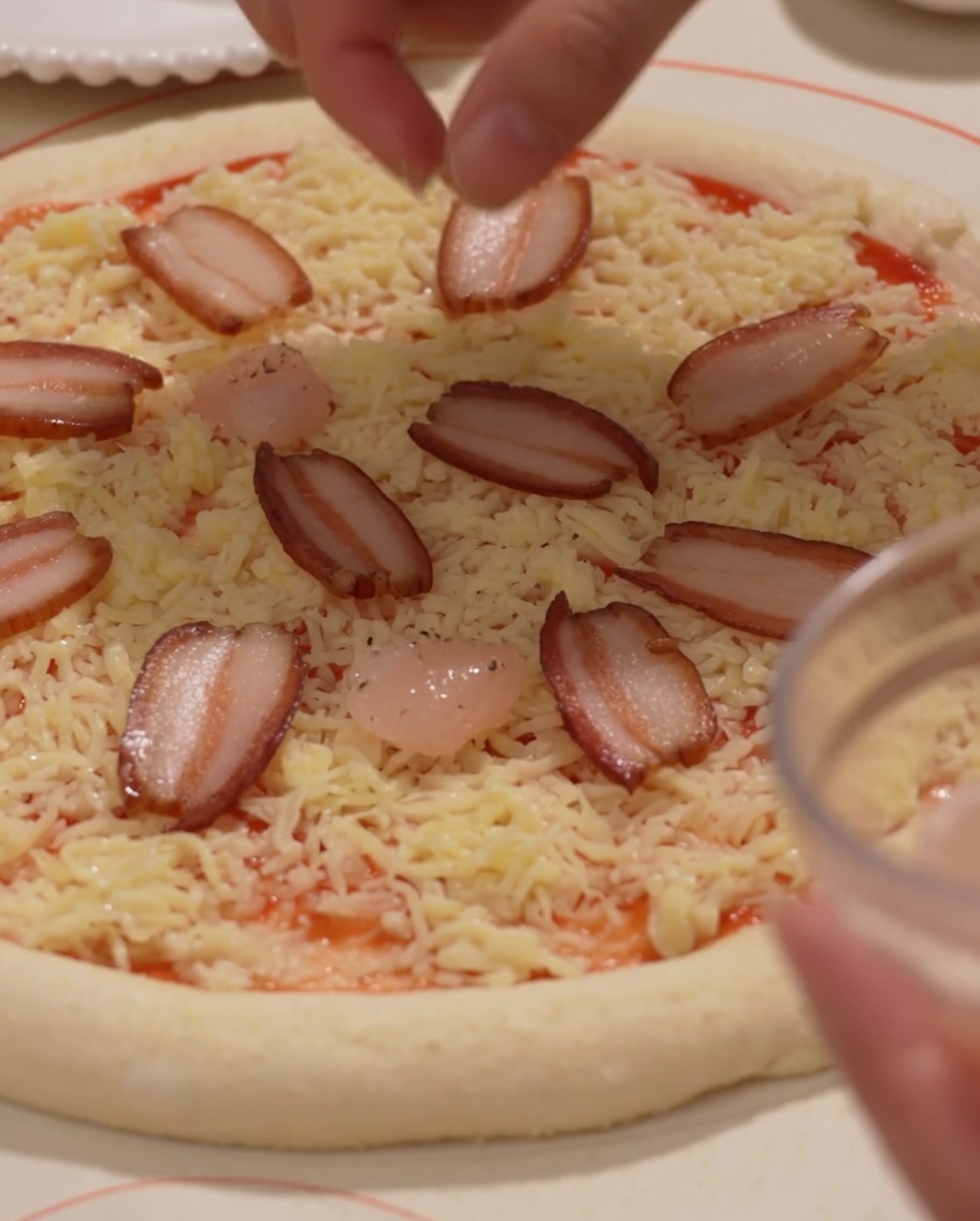 Fette di prosciutto e gamberi posizionati sulla pizza.