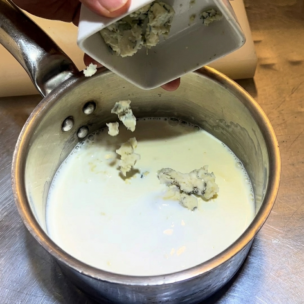 Sbriciolare il gorgonzola nel pentolino con latte e panna.