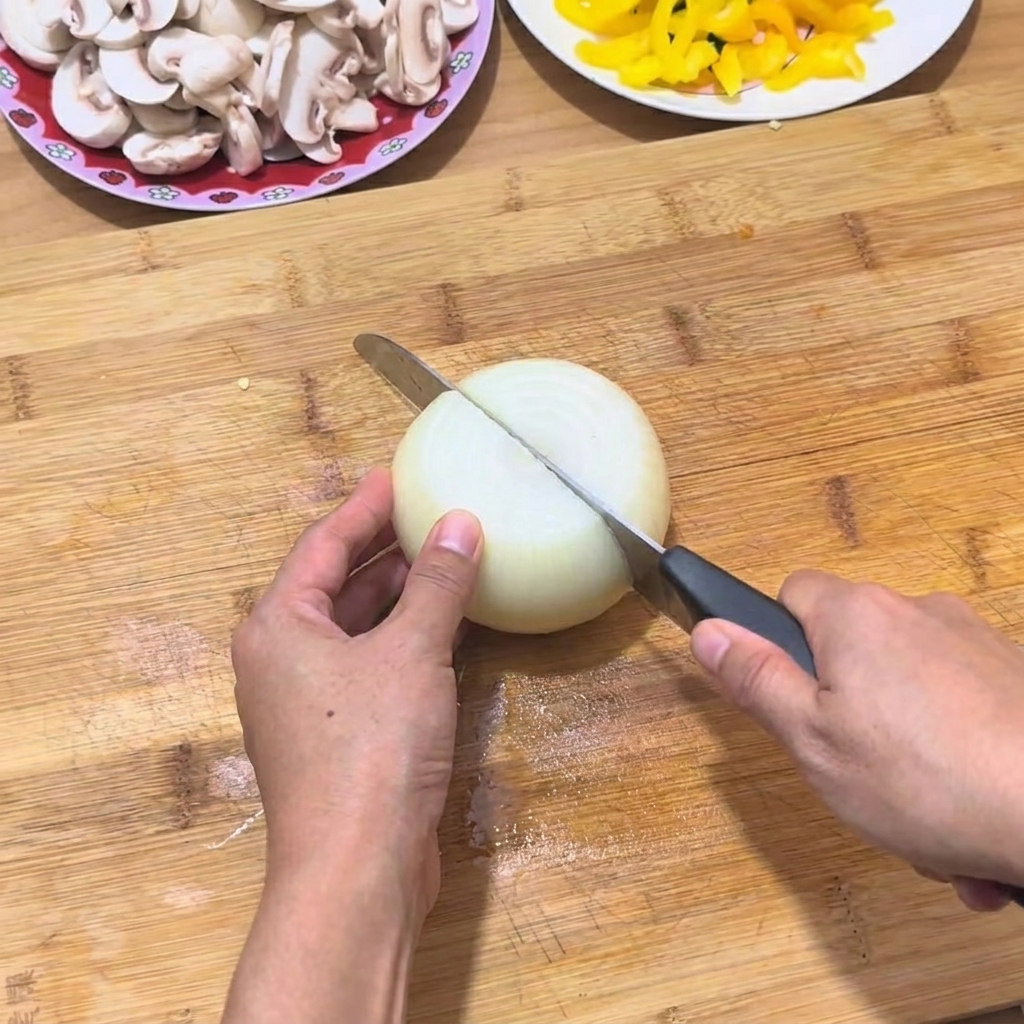 Mani che affettano una cipolla bianca su un tagliere di legno con un coltello affilato.