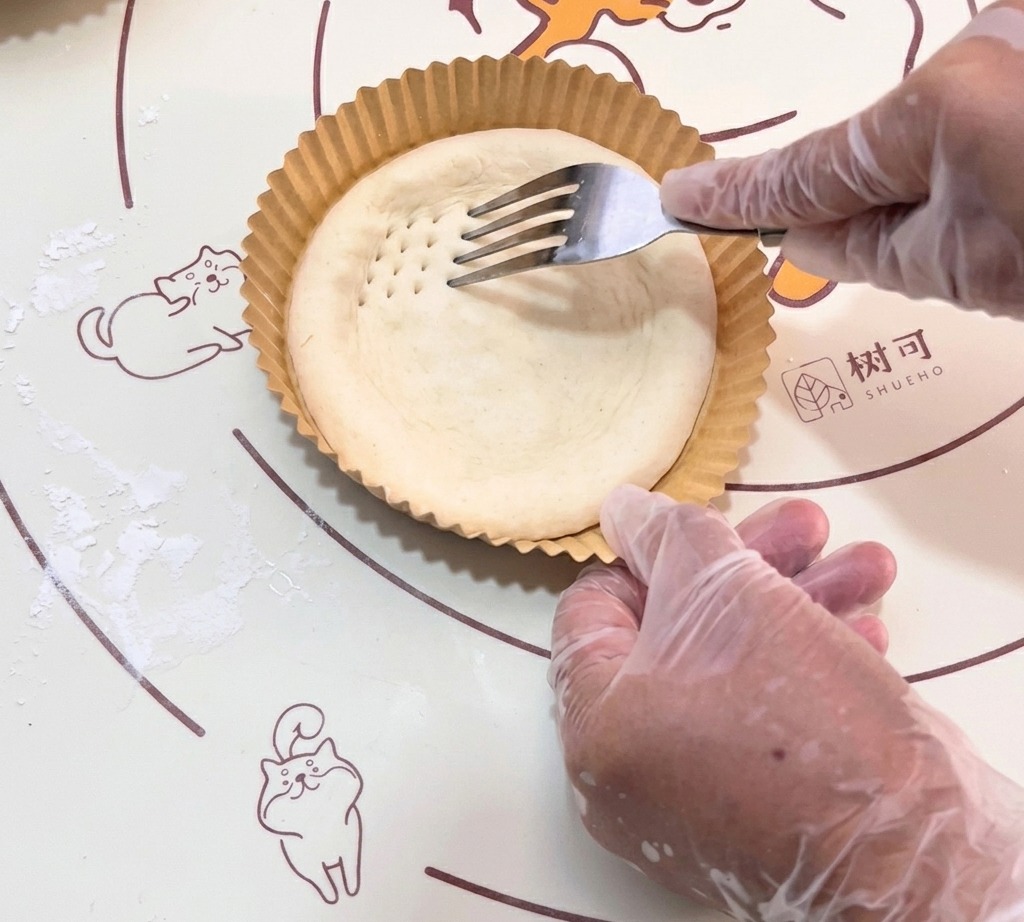 La forchetta che crea piccole rientranze sulla base di impasto crudo.
