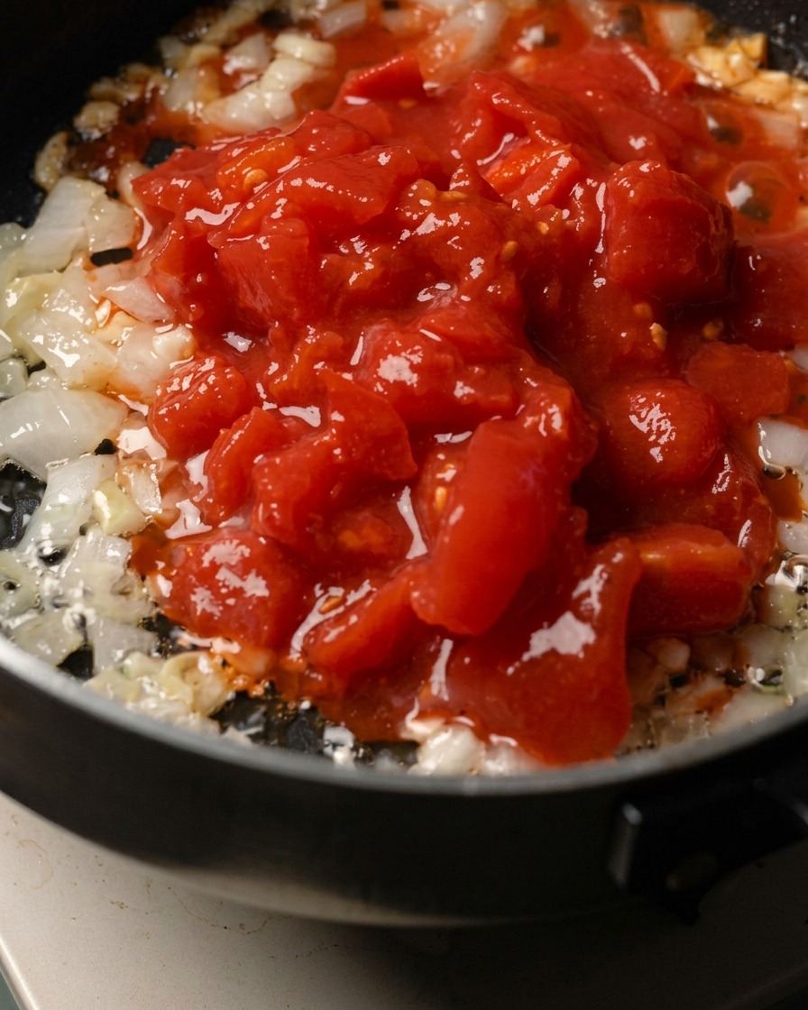 Cipolla tritata, aglio e polpa di pomodoro in cottura in padella.