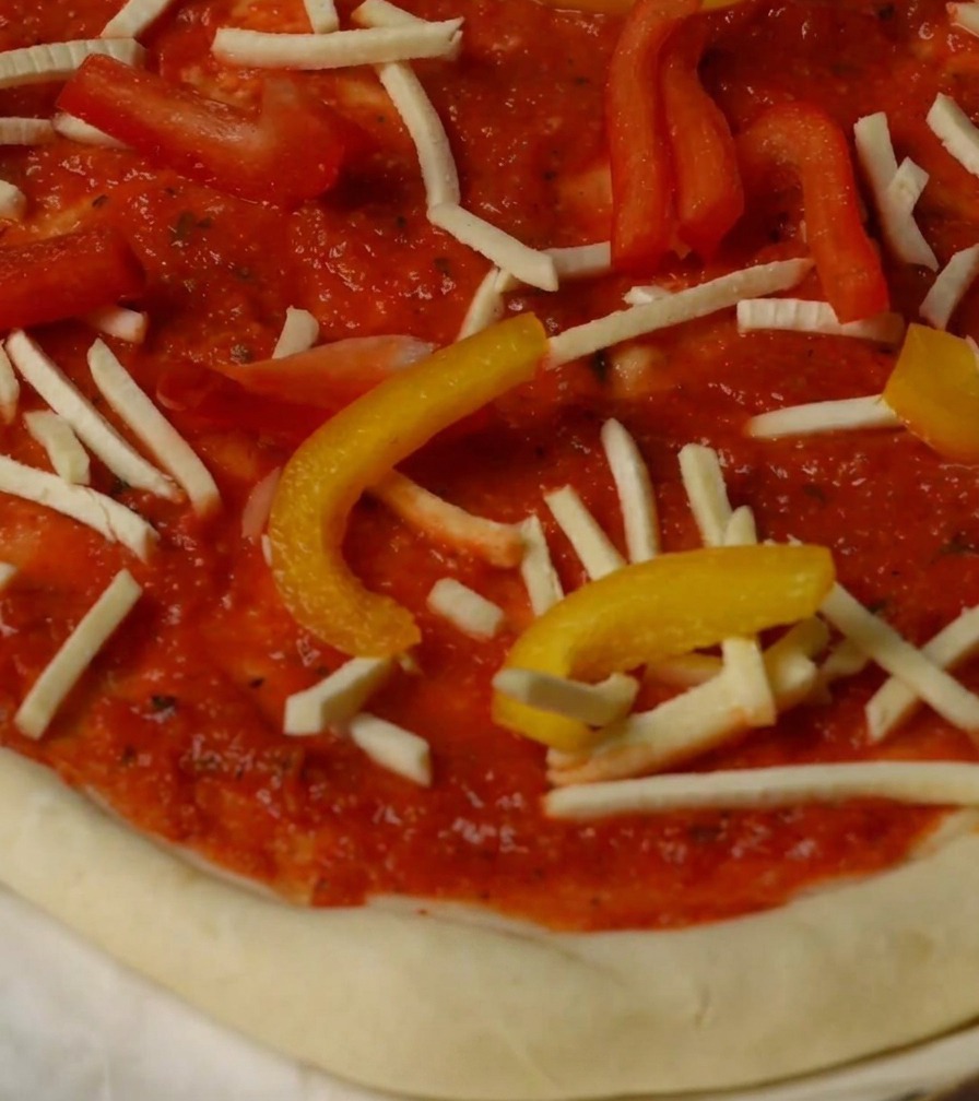 Pizza farcita con peperoni, formaggio e pezzi di astice, pronta per il forno.