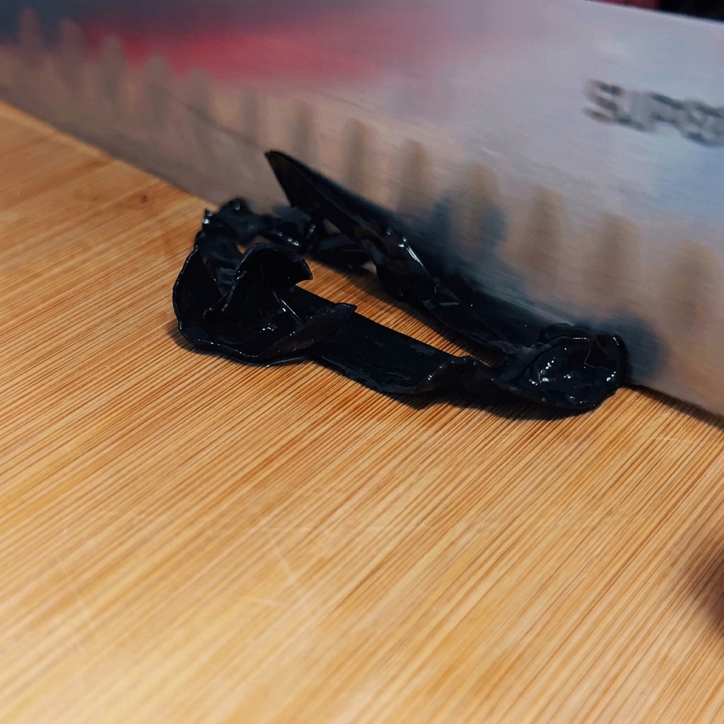 Un coltello affilato che affetta i funghi wood ear sbollentati in strisce sottili e scure su un tagliere.