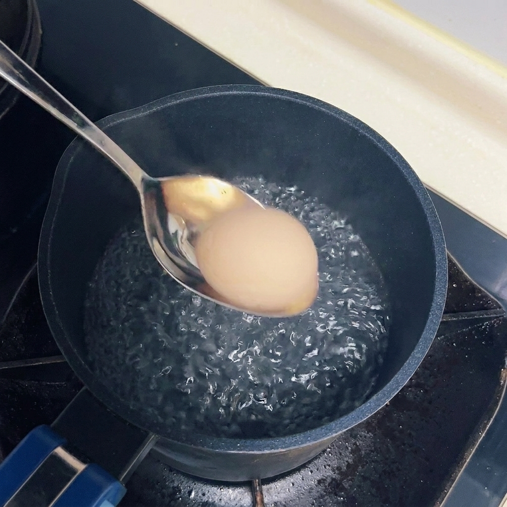 Un uovo che viene immerso con cura in una pentola dacqua che sobbolle dolcemente usando un cucchiaio di metallo.