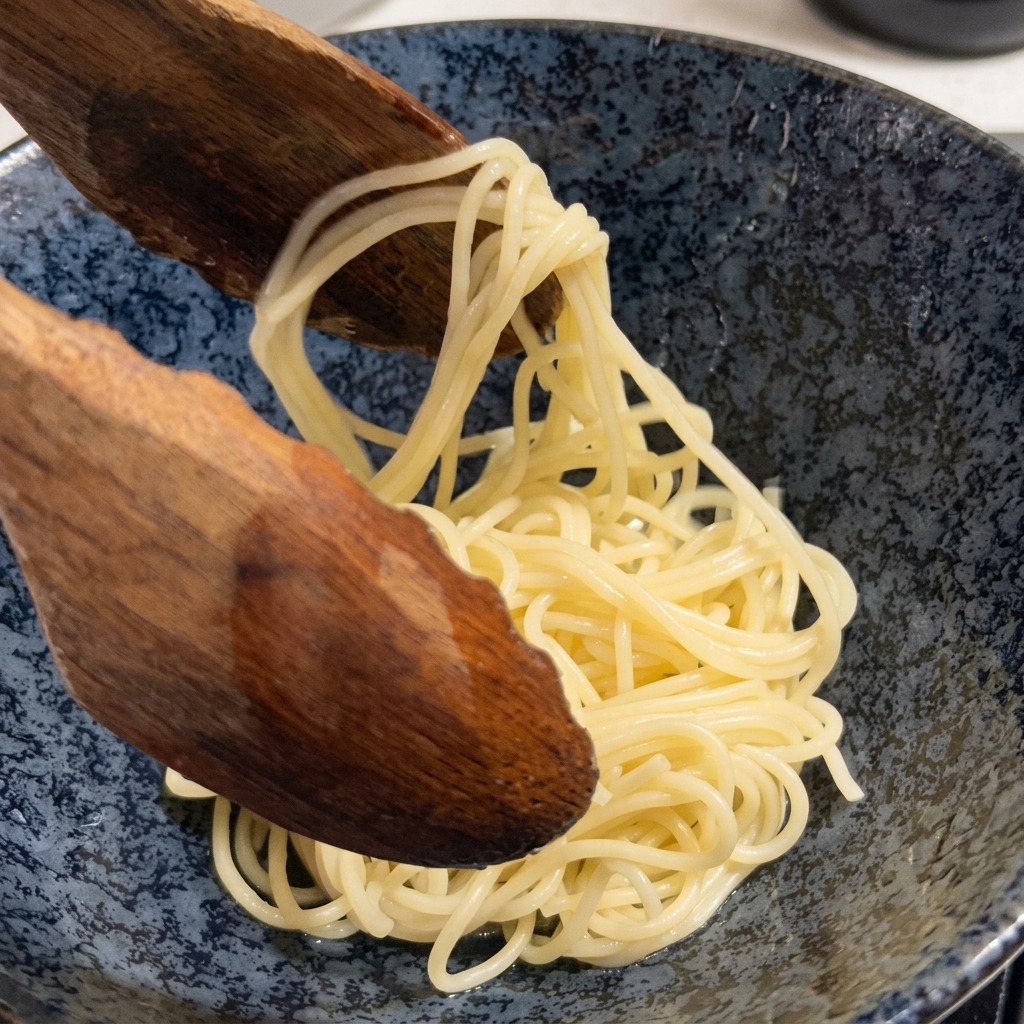 Noodle per ramen cotti estratti da una pentola con un grande cucchiaio di legno.