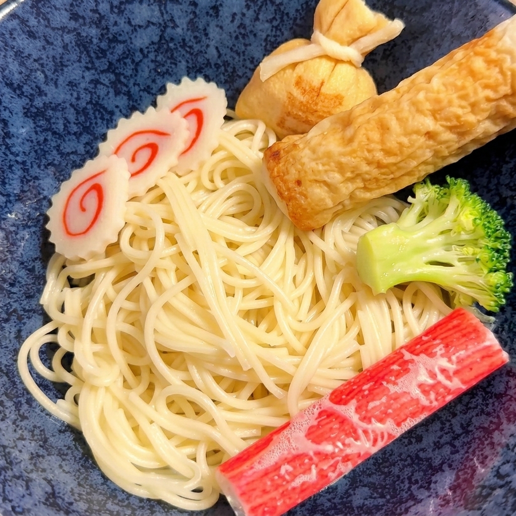 Un paio di pinze che mettono i noodle gialli cotti in una ciotola di ceramica.