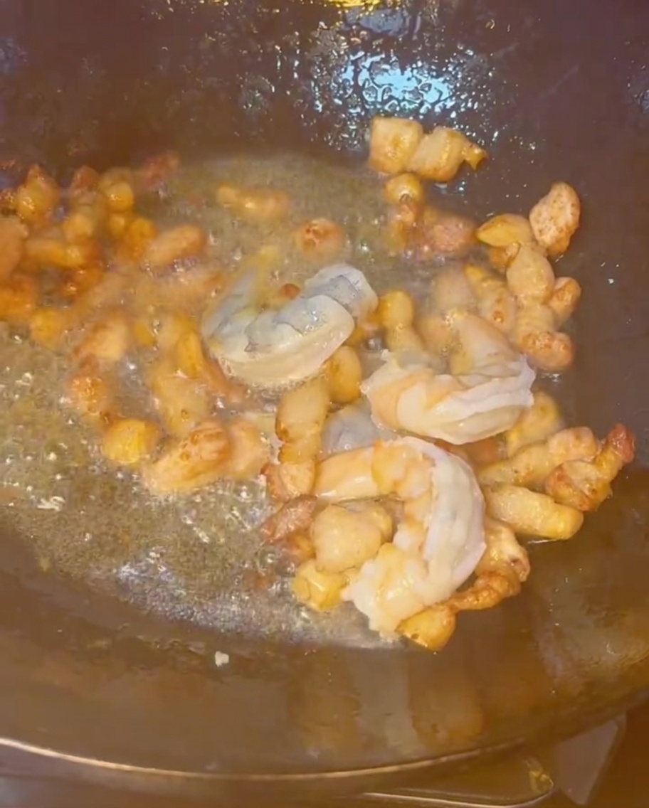 Gamberi, pancetta e altri frutti di mare misti saltati insieme in un wok caldo.