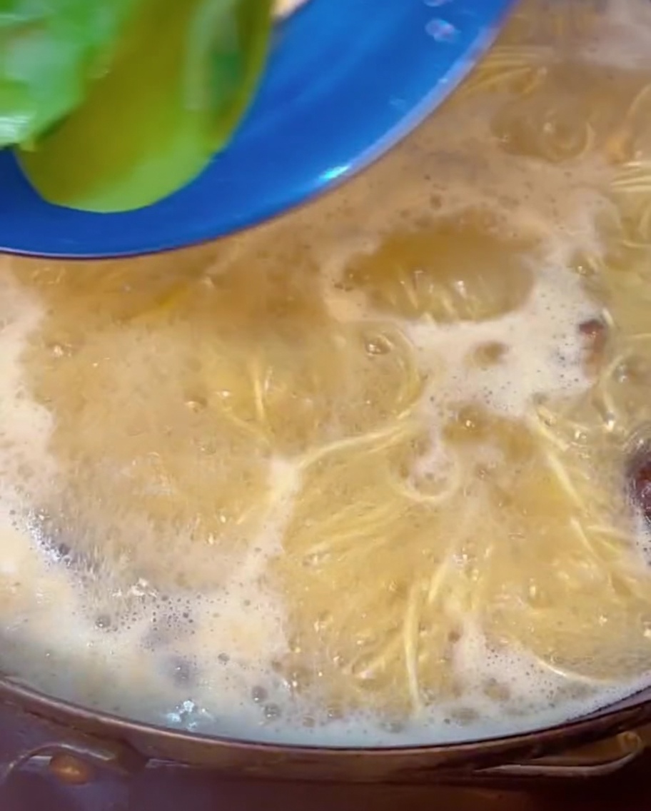 Bok choy verde e fresco immerso in una pentola di ramen e brodo bollente.