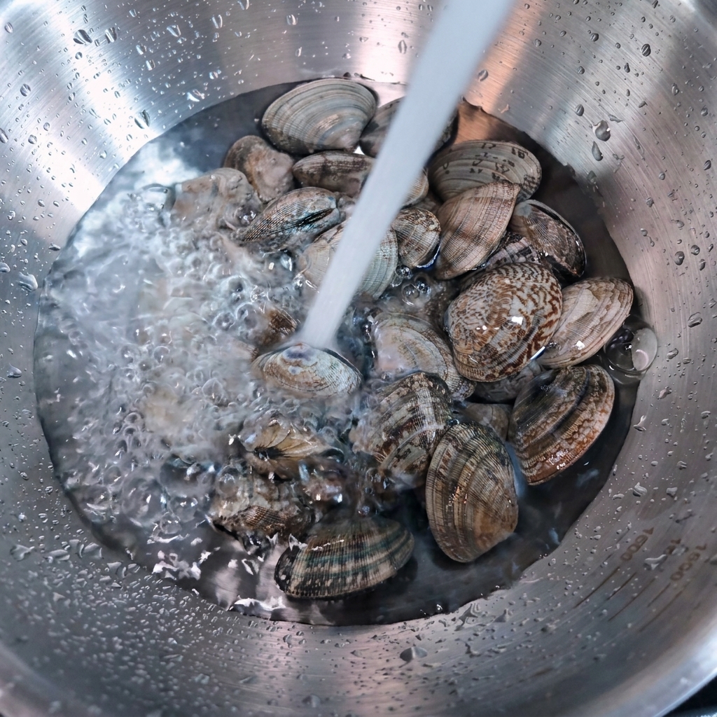 Acqua corrente che scorre sopra le vongole in una ciotola.