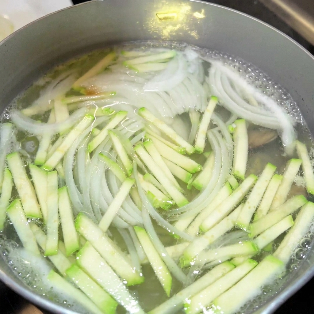 Primo piano dellaggiunta di salsa di soia e colatura di alici in una pentola di brodo.
