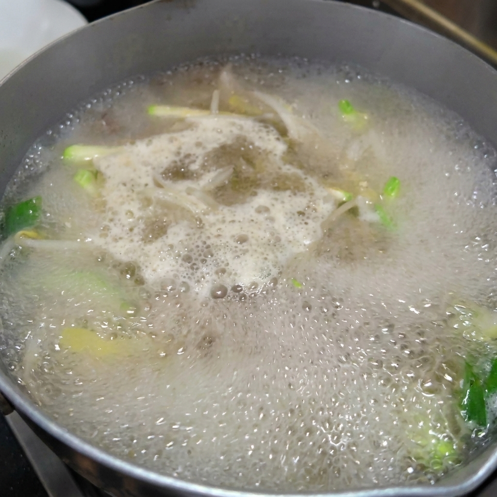 Noodles freschi fatti a mano aggiunti in una pentola di brodo bollente.