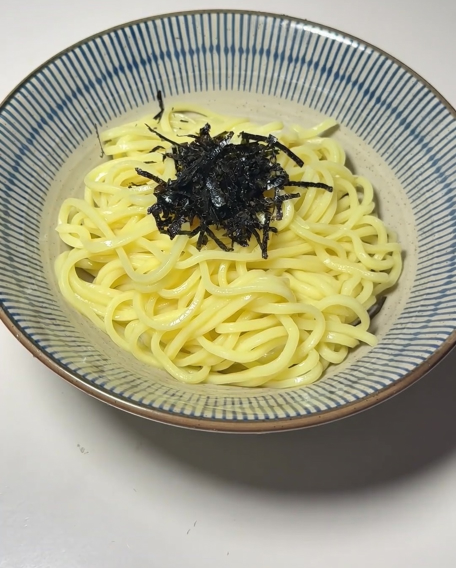 Una ciotola di noodles guarnita con alghe, un uovo barzotto e germogli di bambù.