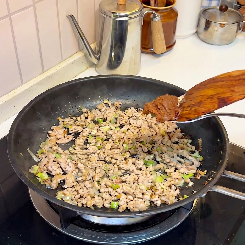 Pasta di miso aggiunta al maiale cotto nella padella.