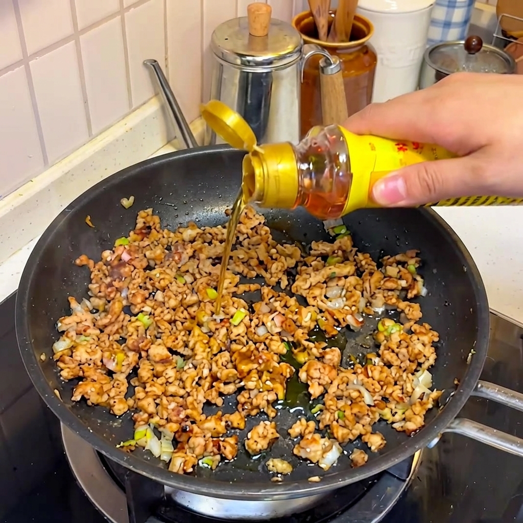 Olio di sesamo e altri condimenti versati sul mix di maiale.