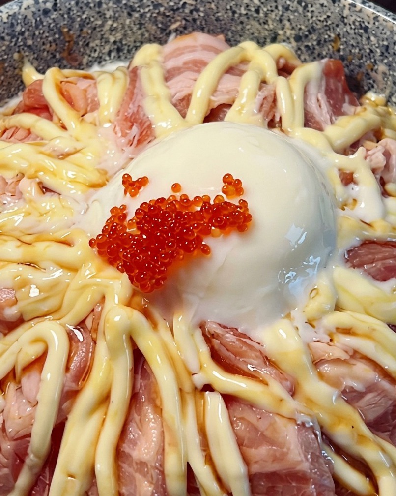 Primo piano di un bowl di salmone sormontato da un uovo morbido e uova di pesce rosse brillanti.