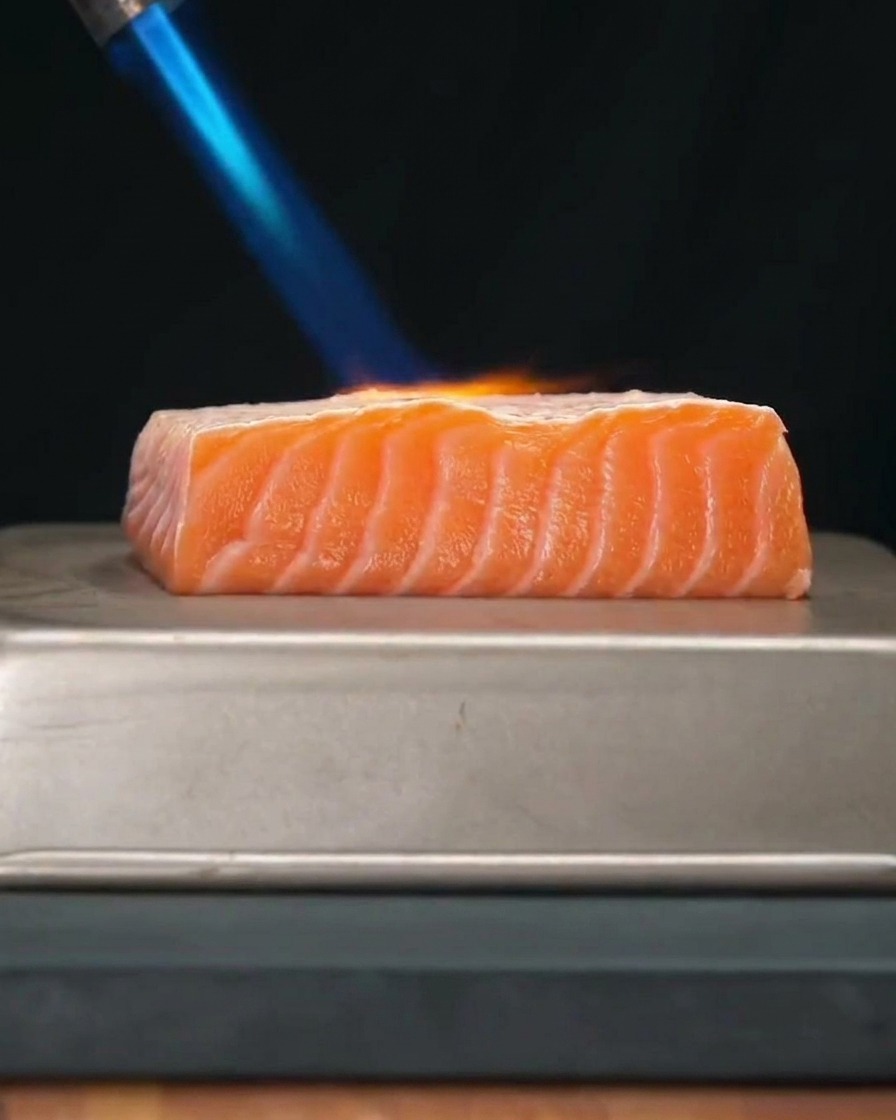 Filetto di salmone fresco e spesso scottato con la fiamma azzurra di un cannello da cucina.