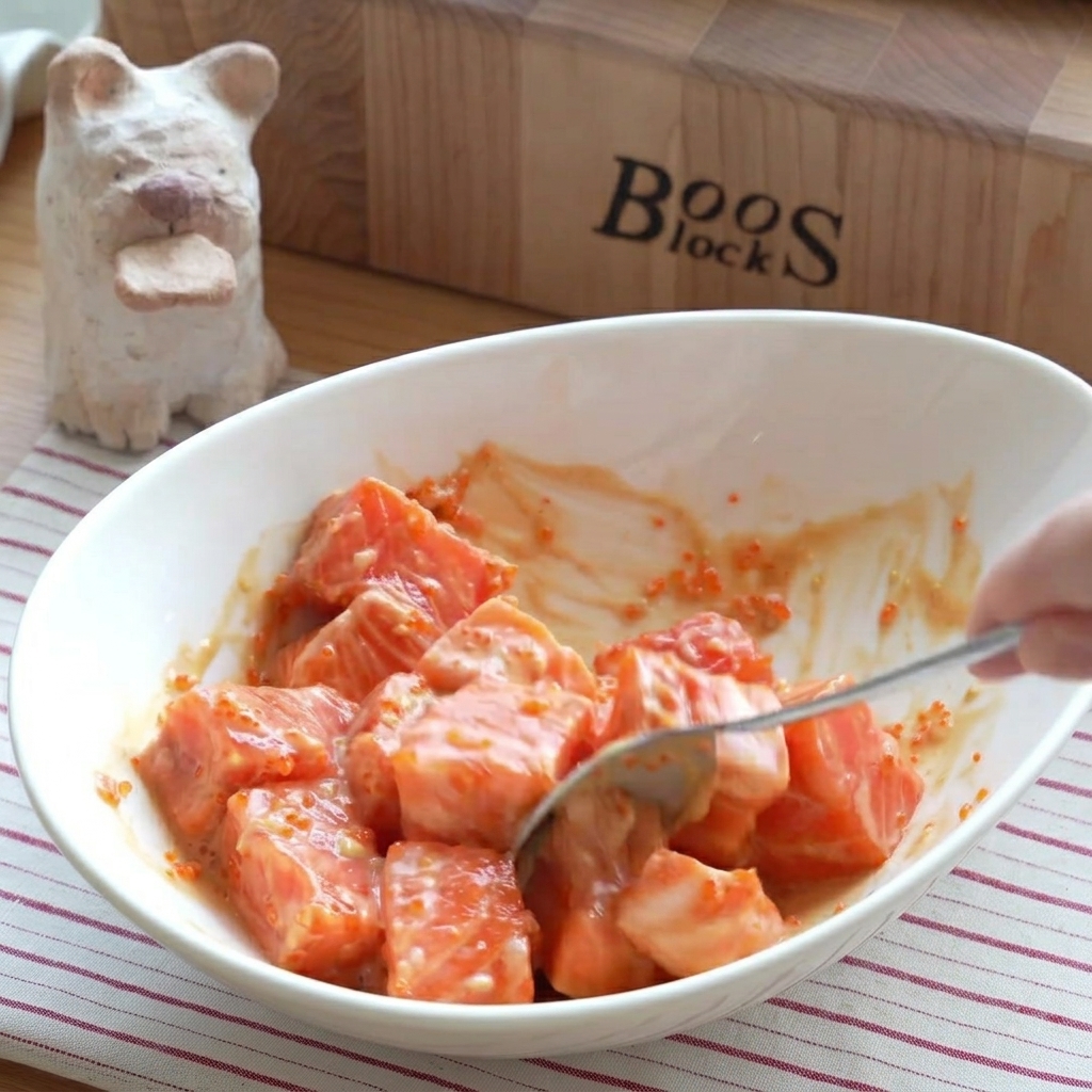 Primo piano di cubetti di salmone conditi e mescolati delicatamente in una ciotola.