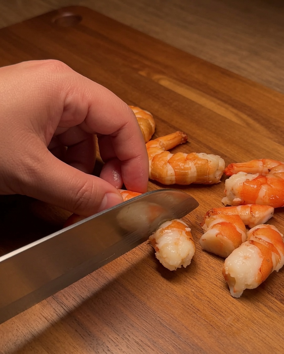 Filetto di salmone crudo tagliato in cubetti netti e uniformi su un tagliere di legno.