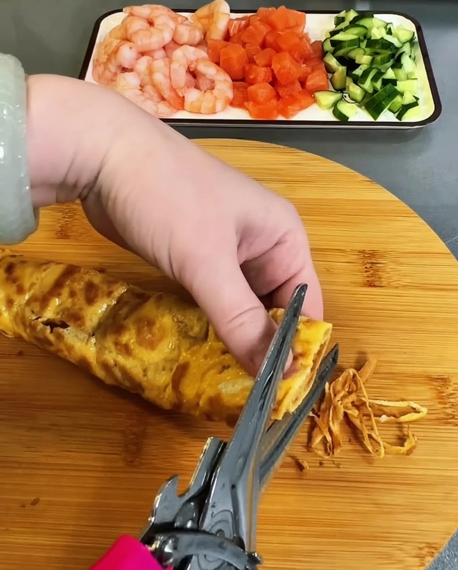 Frittata cotta tagliata in strisce sottili con forbici da cucina.