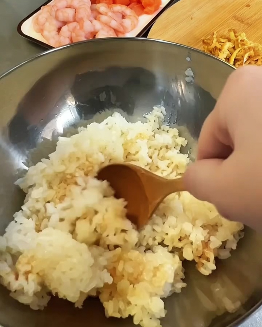 Riso cotto condito con aceto e salsa di soia in una ciotola di metallo.