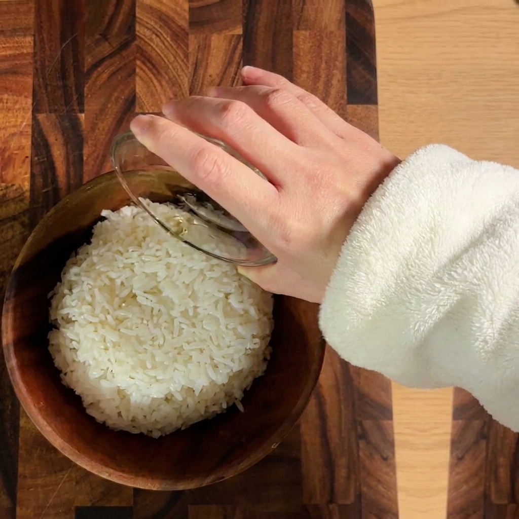 Riso bianco cotto condito con aceto per sushi in una ciotola di legno.