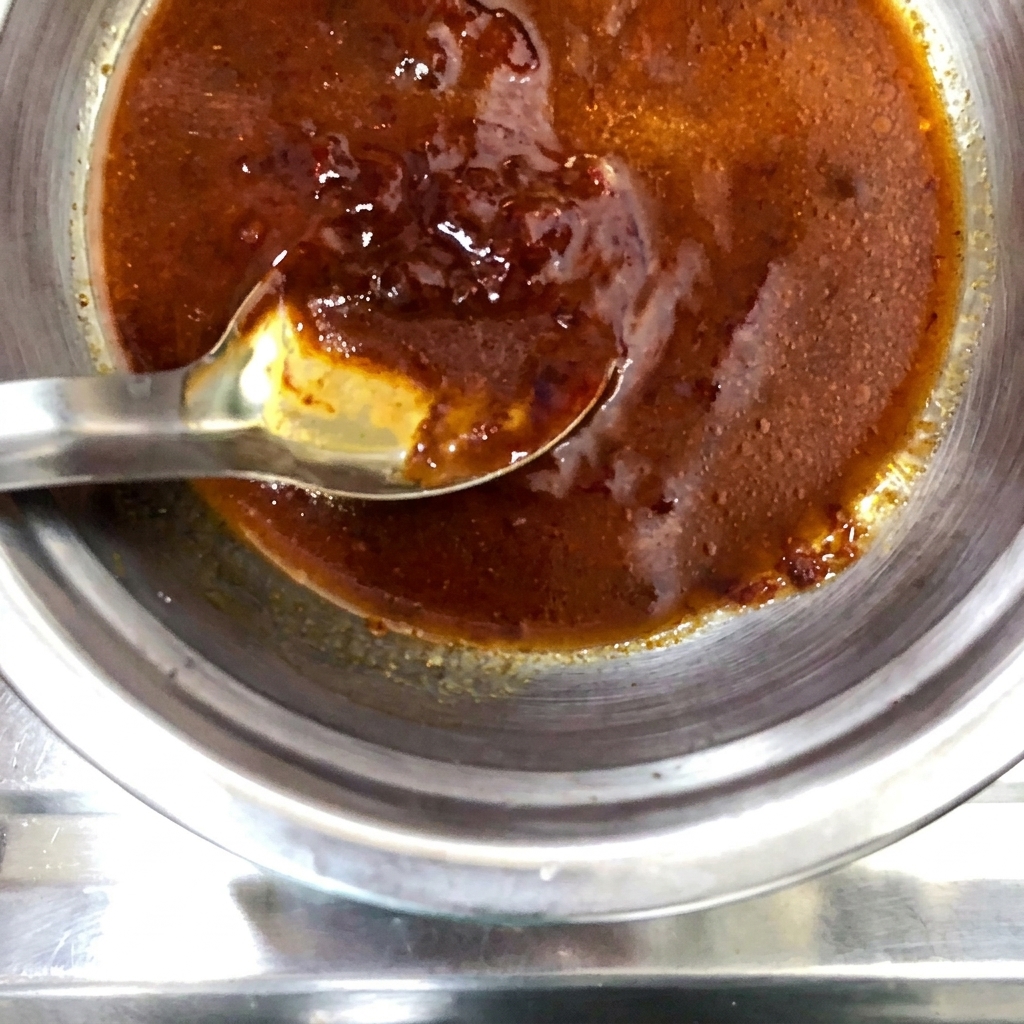 Una polvere di spezie secche cosparsa sopra il composto di salsa preparato nella ciotola di metallo.