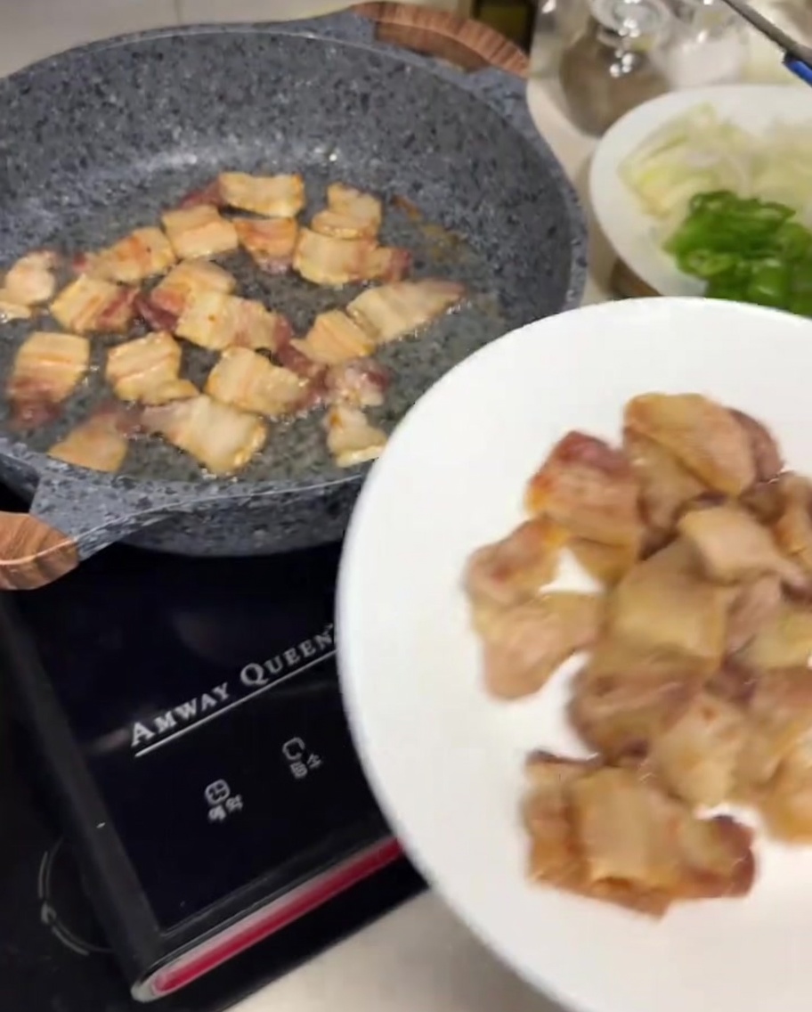 Pinze di metallo che posizionano fette di pancetta croccanti su un piatto bianco.