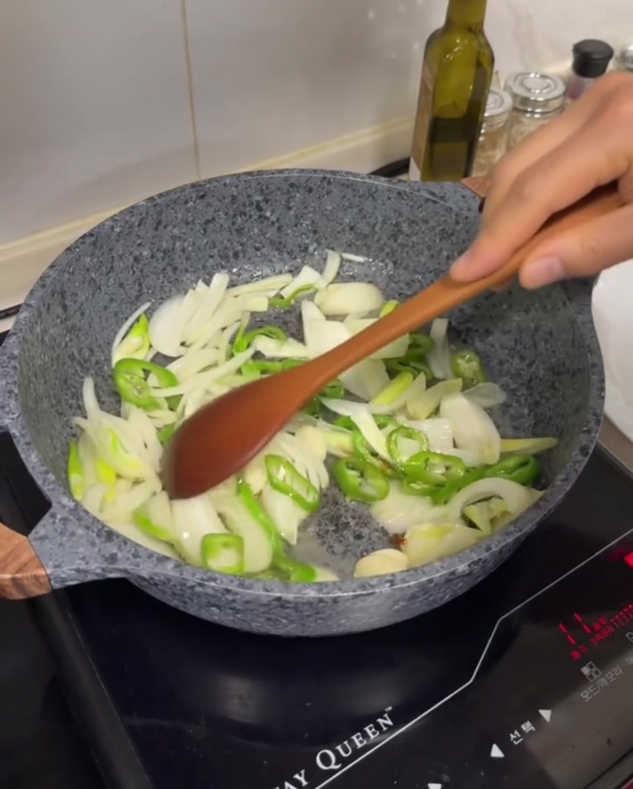 Cipolle bianche affettate, peperoncini verdi e spicchi daglio saltati in padella con il grasso sciolto.