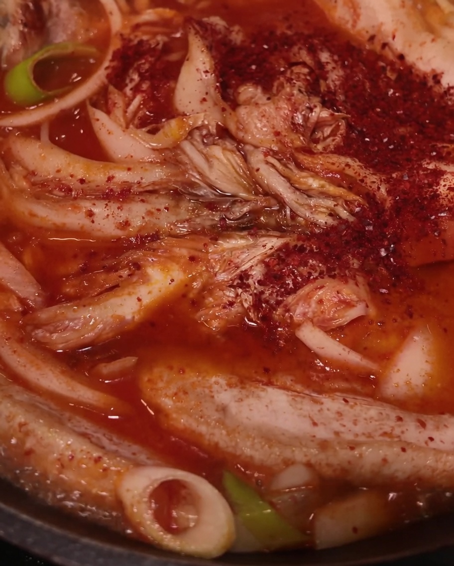 Peperoncino rosso in polvere spolverato sopra la carne, il kimchi e le cipolle.