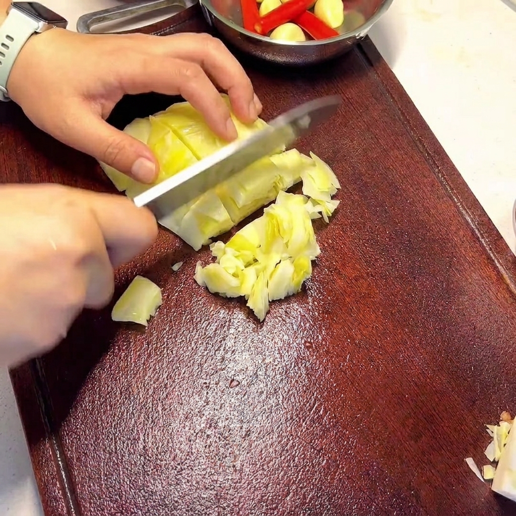Mani che tengono un coltello e affettano pezzi di crauti verde chiaro su un tagliere di legno scuro.