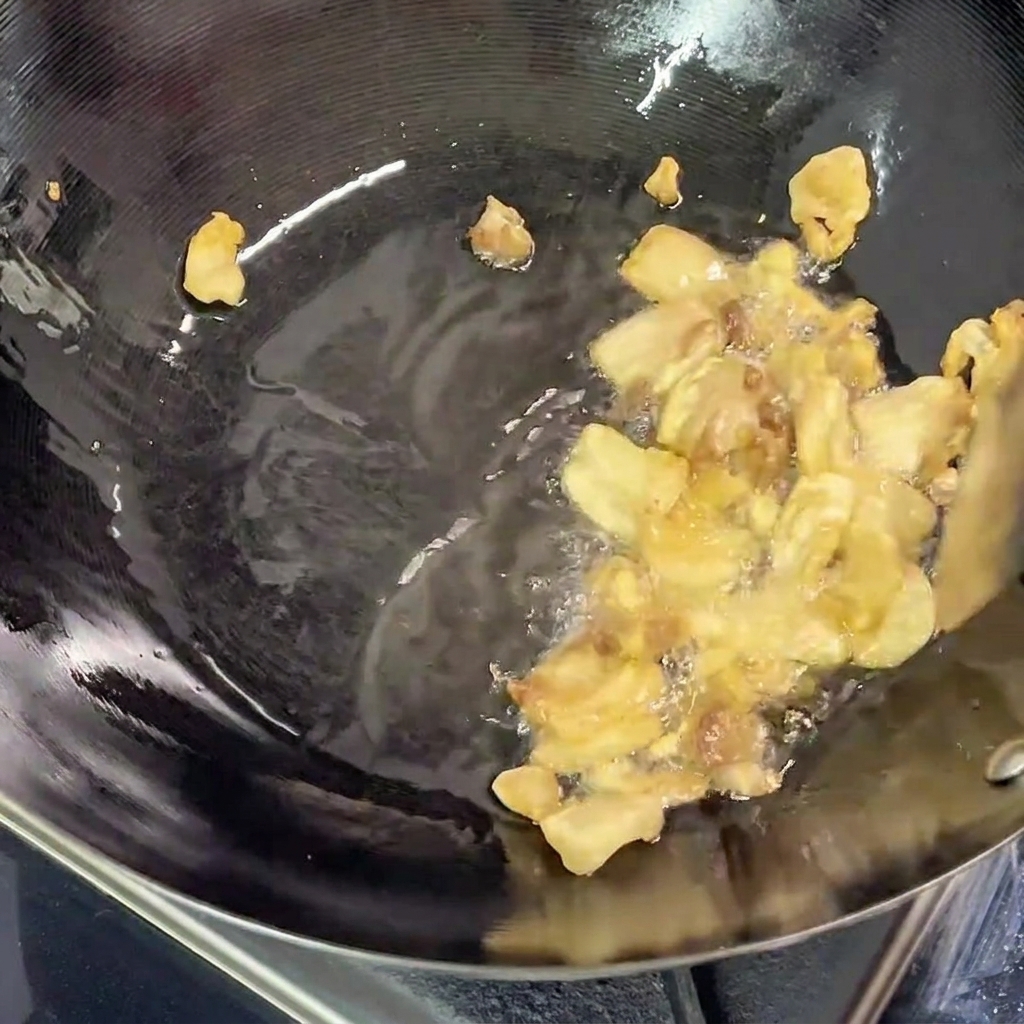Pezzi di pancetta che friggono nel wok, con grasso sciolto visibile sul fondo della padella.