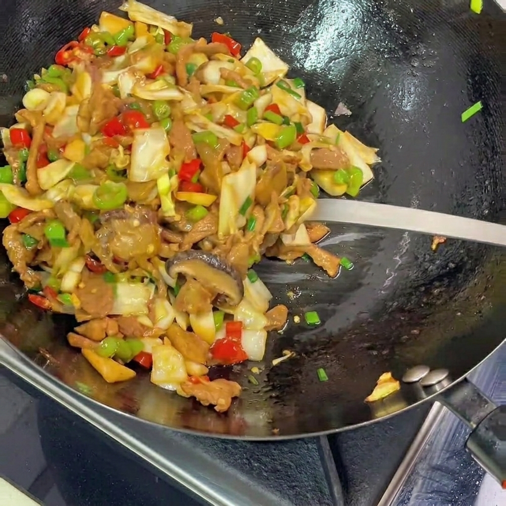Una spatola di metallo che raccoglie un mix colorato di crauti saltati, maiale e peperoni da un wok nero su un piatto.