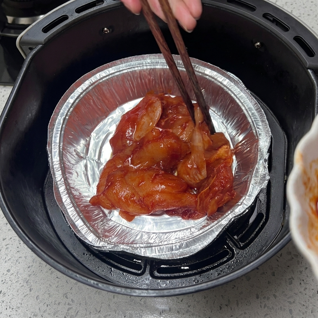 Bacchette di legno dispongono il pollo marinato in una vaschetta di alluminio.