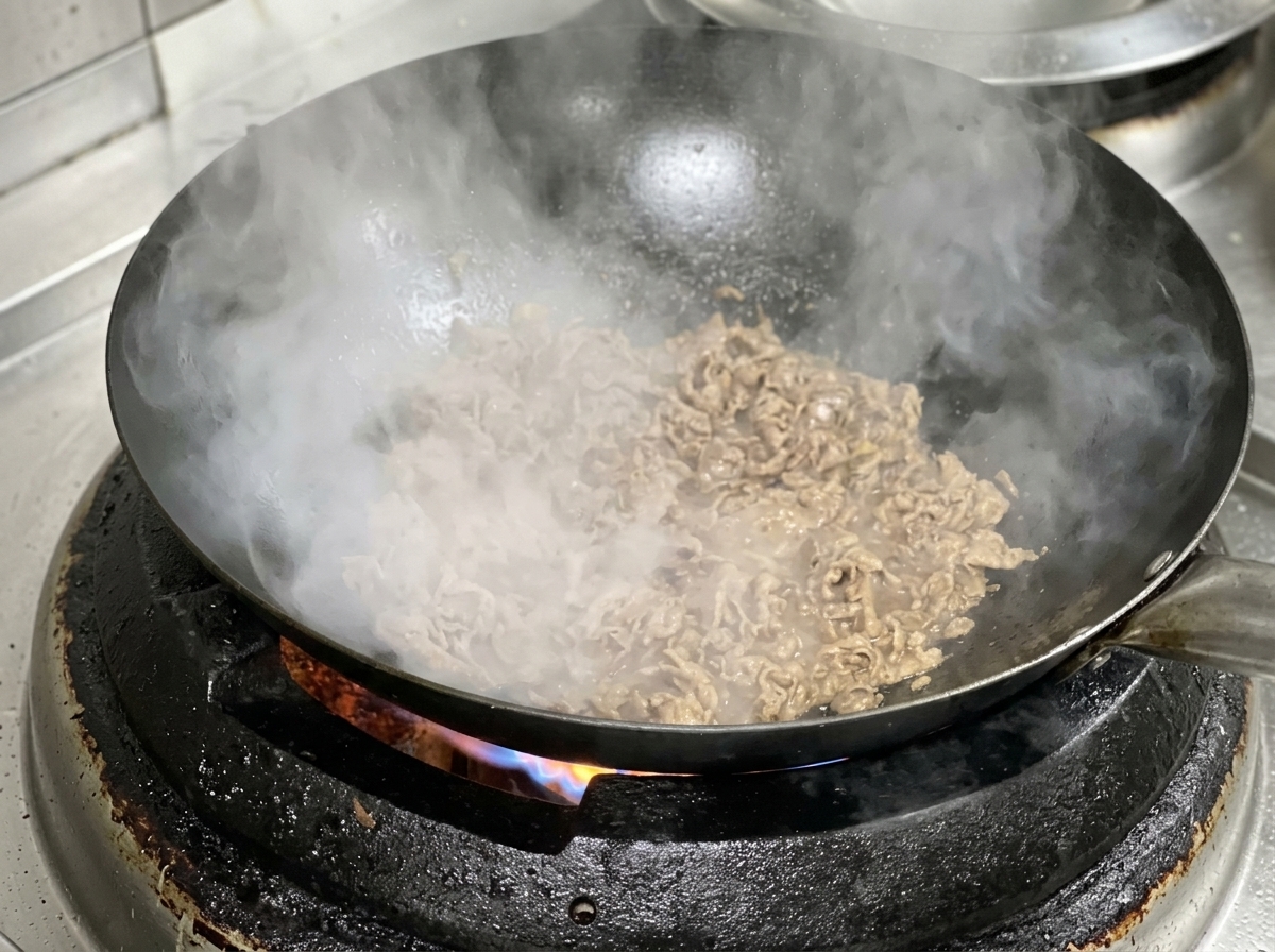 Fette di manzo e cipolla che cuociono insieme in un wok bollente.