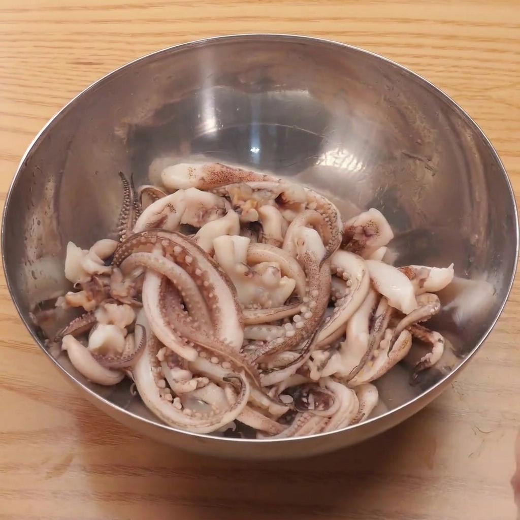 Tentacoli di calamaro freschi immersi in una ciotola di acqua bollente per una rapida sbollentata.
