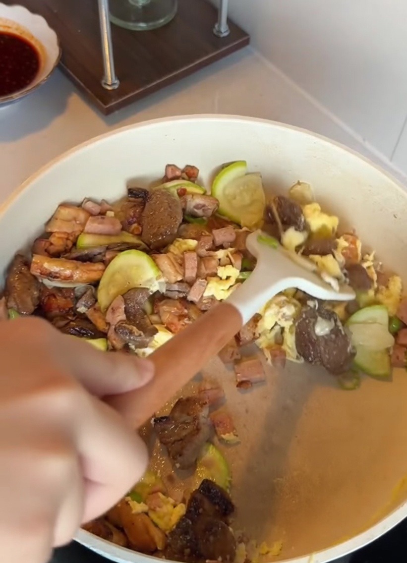 Una ciotola di riso bianco aggiunto a una padella contenente zucchine, carne e uova.