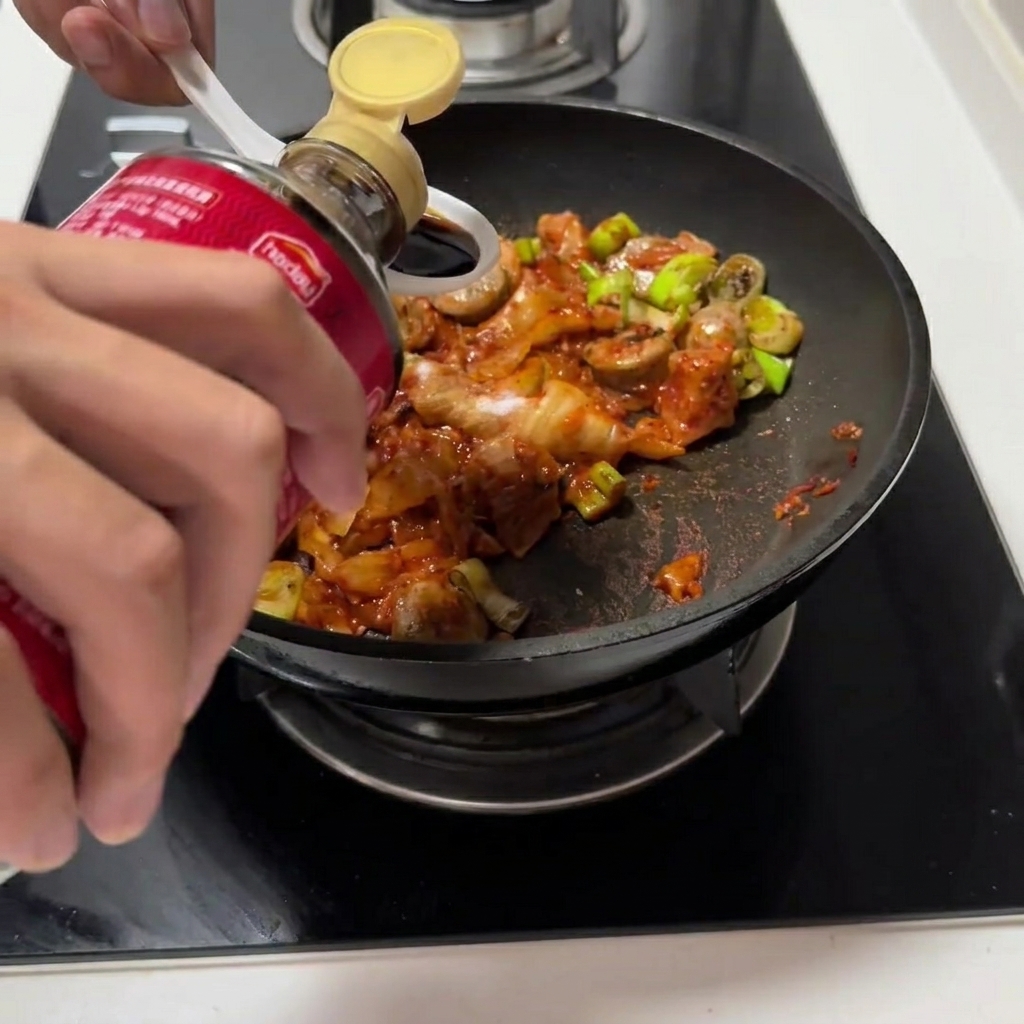 Salsa di soia e salsa di ostriche versate nella padella con il composto di kimchi.