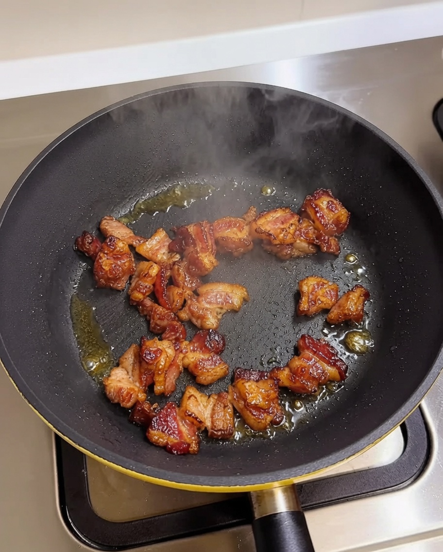 Pezzi di pancetta che rosolano in una padella calda.